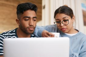 Young couple sitting at home and looking together at mortgage rates online