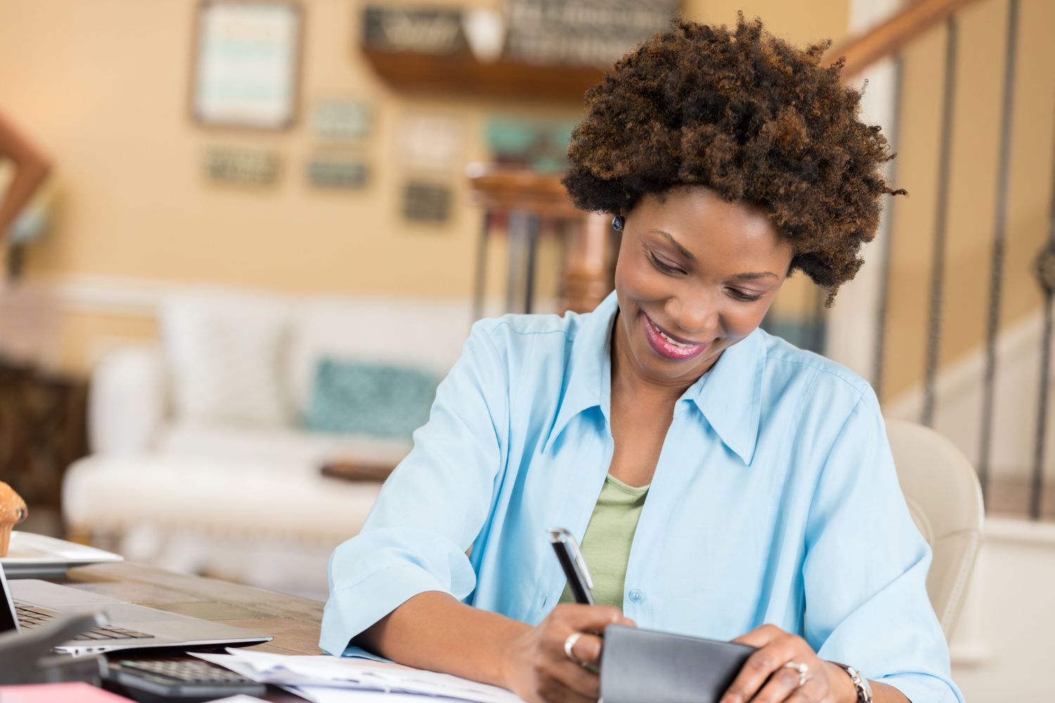 Woman sitting at a desk at home, writing a check to a charity