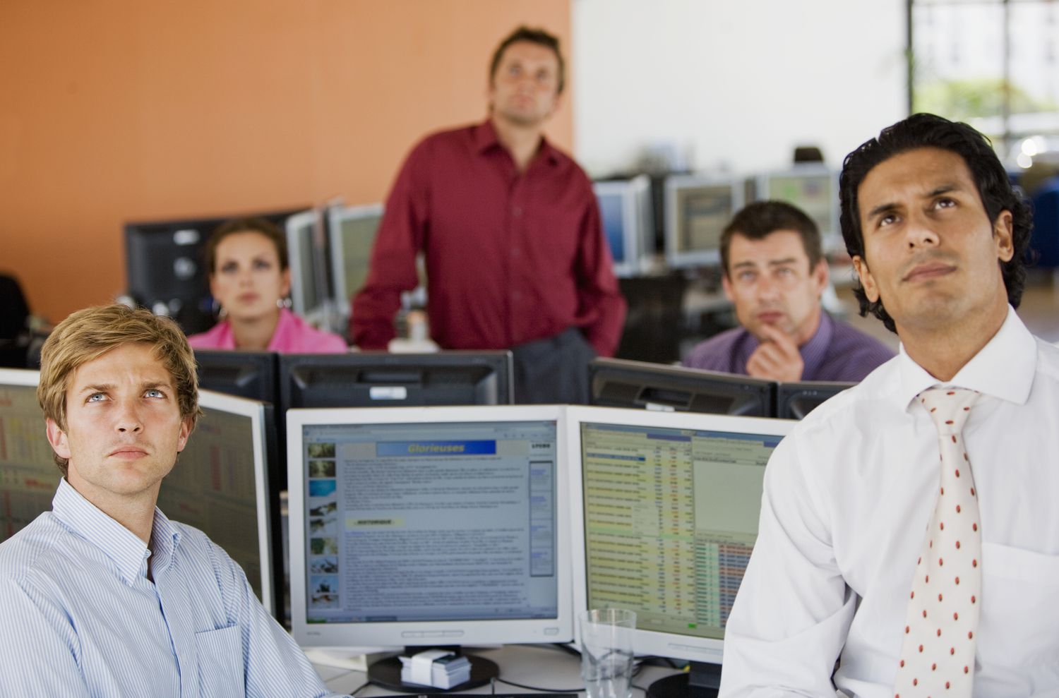 Several traders in the trading room of a brokerage firm watch a report from the Federal Open Market Committee to see is interest rates will change.