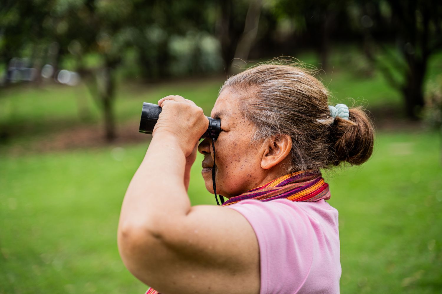 Older woman looking through binoculars outdoors 