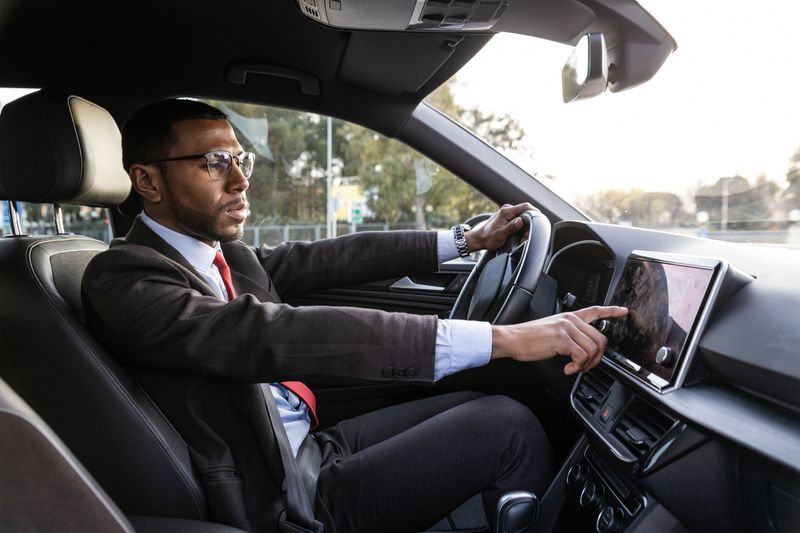 A man driving a car adjust the dashboard settings.