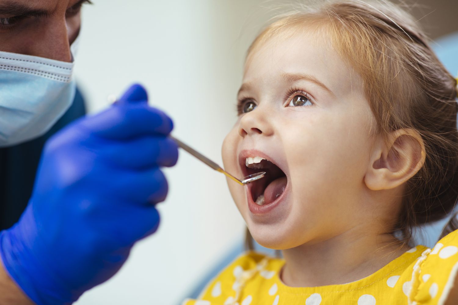 A stock image of a young girl getting a checkup from a dentist. 