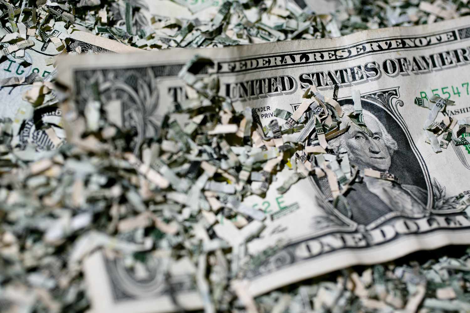 Shredded currency surrounds a U.S. one dollar bill.