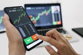 Image showing hands holding a mobile phone displaying a trading app.