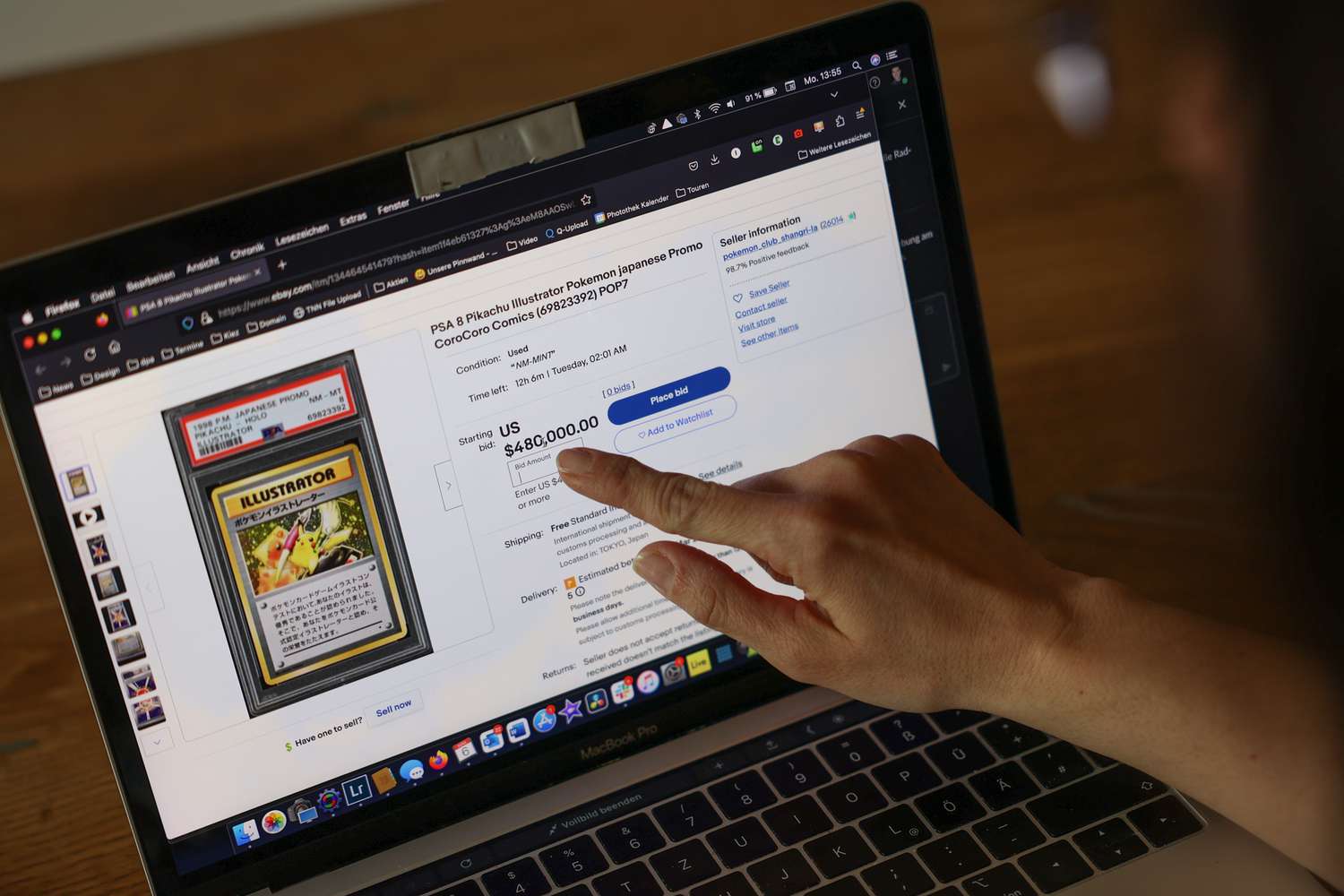 A woman points to an eBay listing for a "Pikachu Illustrator" card in 2023. 