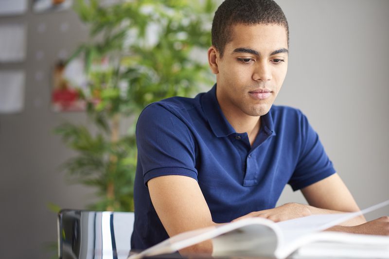 A student studying a book on his desk.