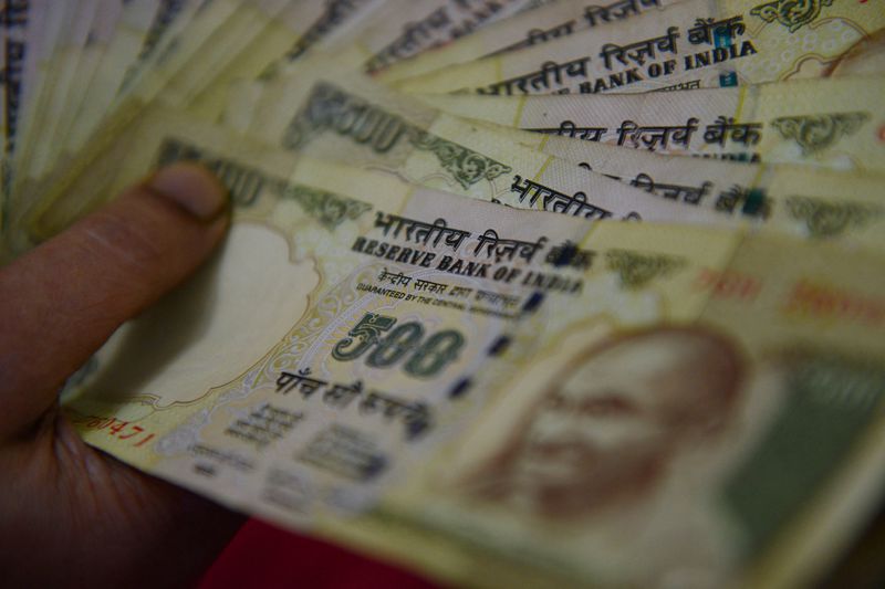 Finger on rupee notes spread fan like