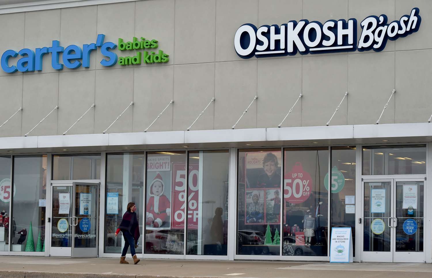 A person walks in front of a pair of Carter's Babies and Kids and OshKosh B'Gosh stores.