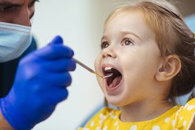 A stock image of a young girl getting a checkup from a dentist. 