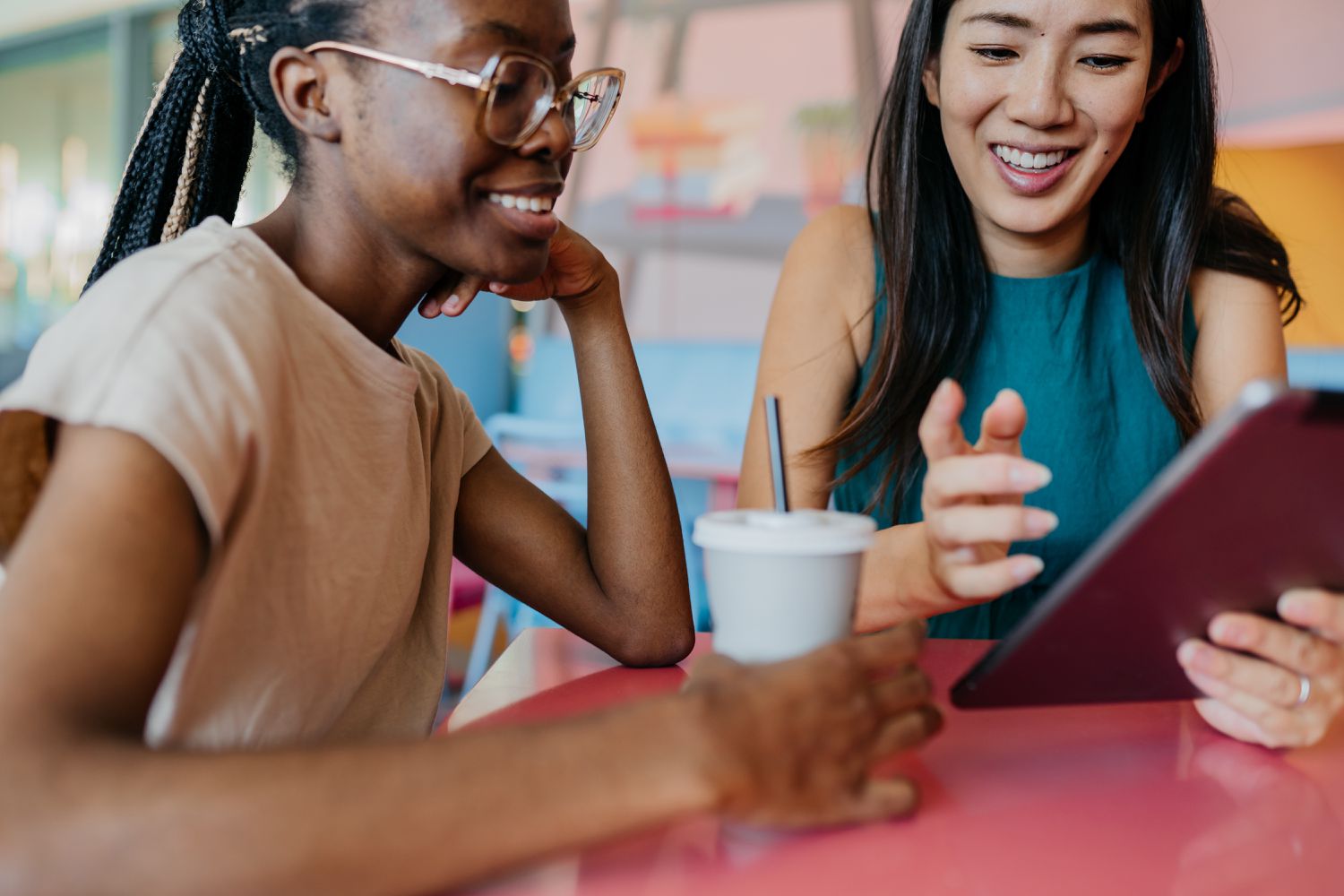 Two young woman having a coffee break and using a digital tablet