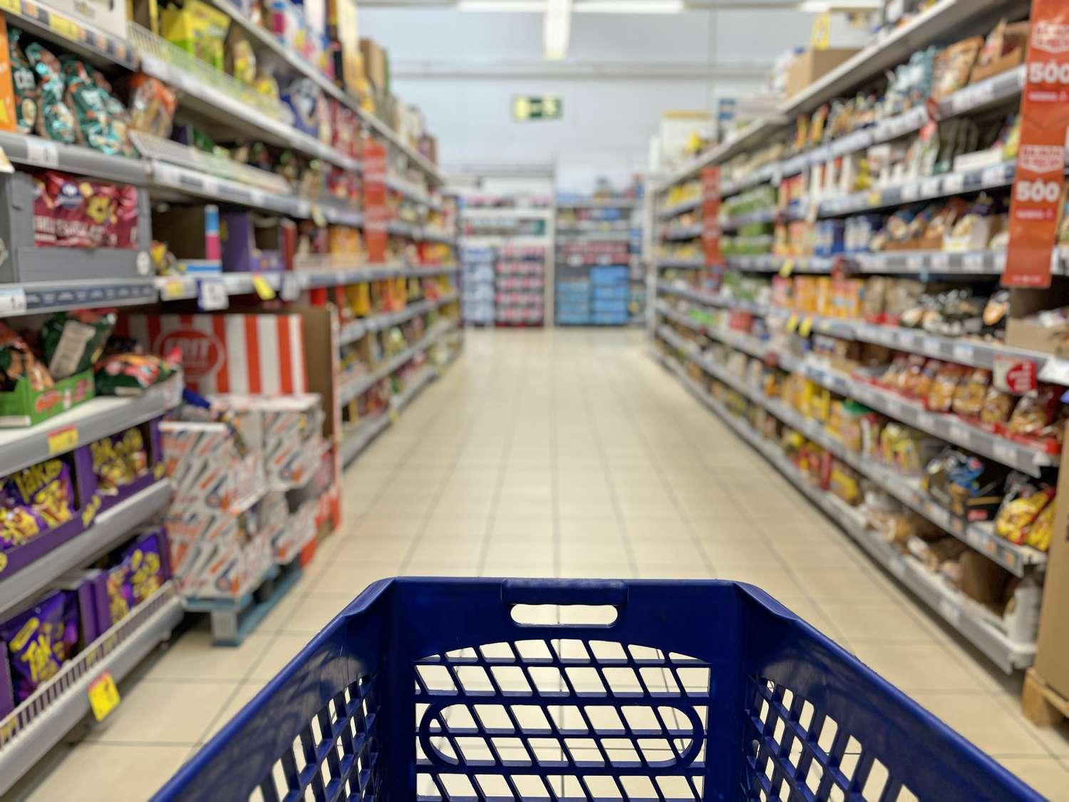A stock image of a cart in a grocery store aisle. 