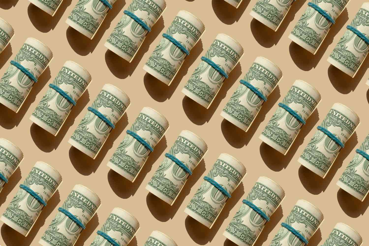 Rows of rolled American dollars on a beige background