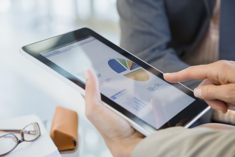 Business people reviewing financial data on digital tablet.