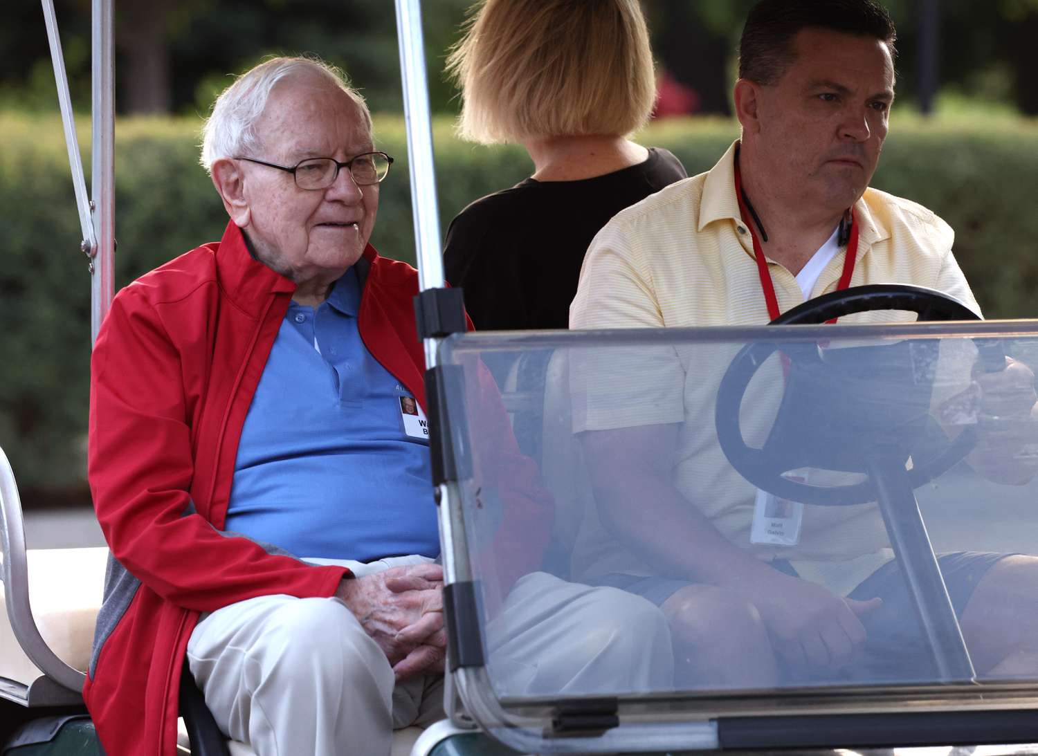 Warren Buffett being driven in a golf cart.