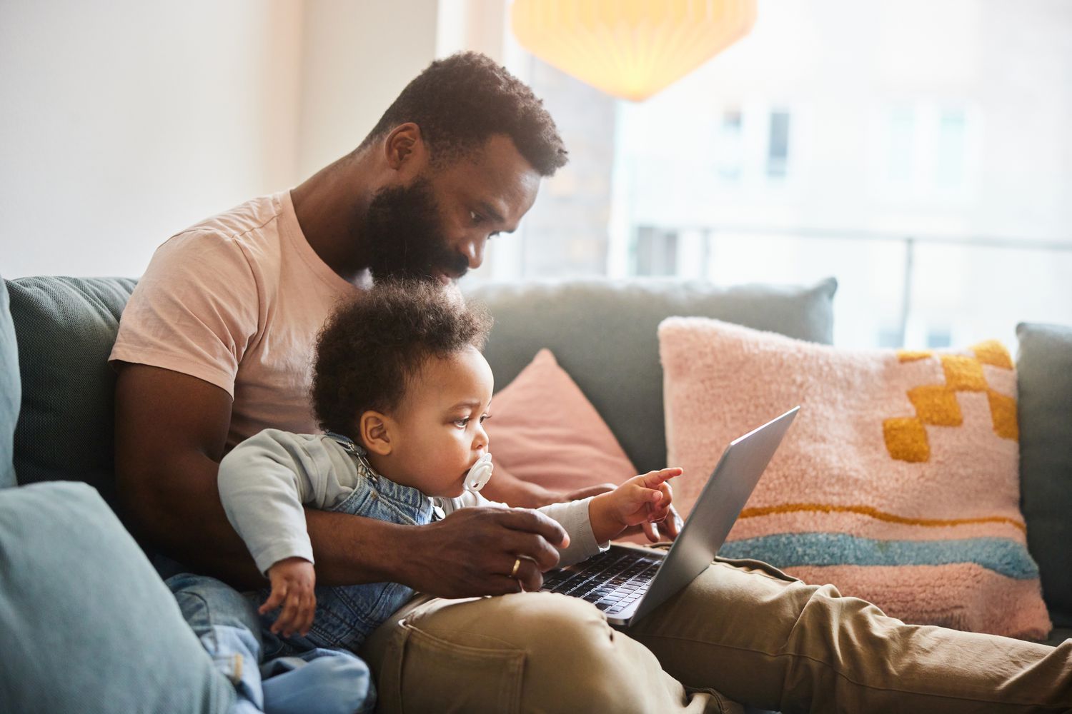 Father working on laptop with infant son