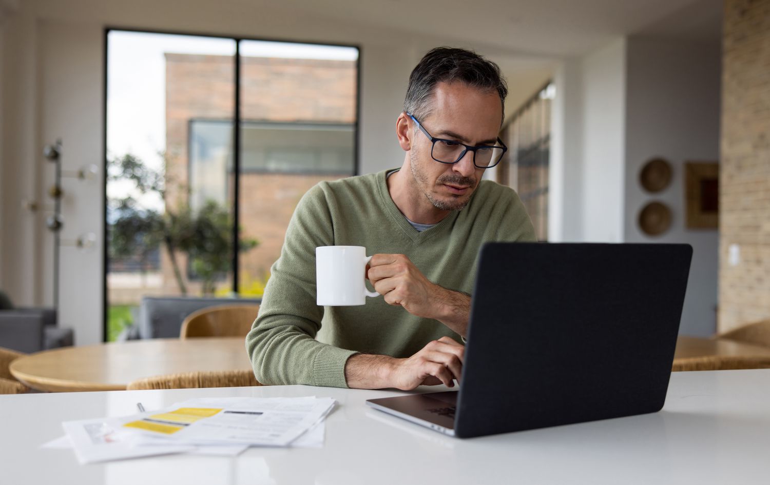 Man in his 40s or 50s, sitting at home and looking seriously at bank rates on his laptop