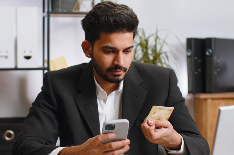 Business man making online payment with business credit card and smartphone at office