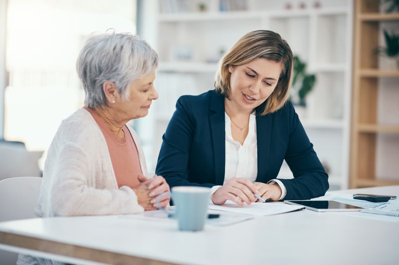 A financial advisor sits at a dining room table and talks with a mature adult client about rolling their TSP into a Roth IRA plan.