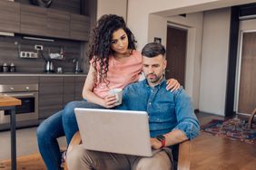 Couple reading about who regulates mortgages on their laptop