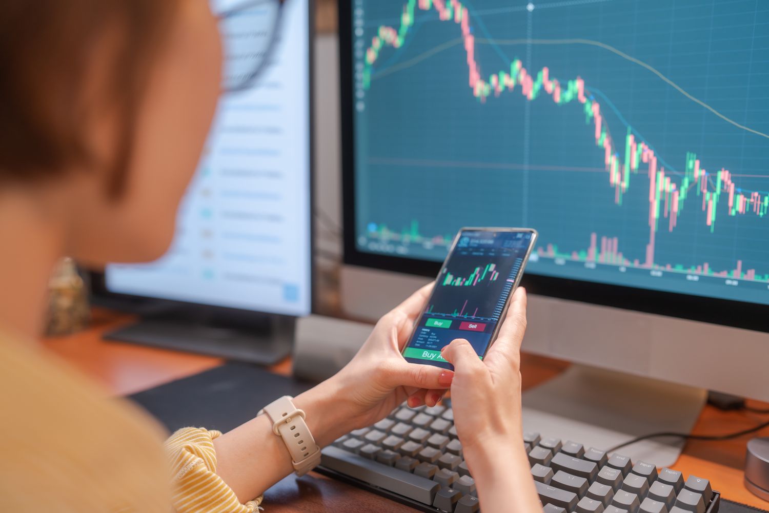 Trader entering Buy order on mobile trading app following the trends displaying on stock chart.