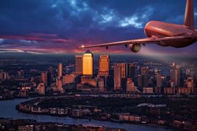 A commercial airplane jetliner flying above business district of London.