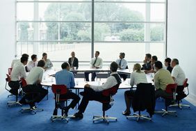 Businessmen and women in meeting at large circular table