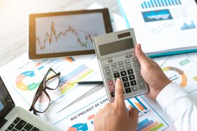 A businessman accountant using a calculator and a laptop for calculating finance on a desk office.