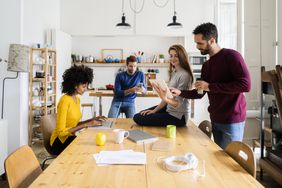 Friends hangs out in the dining room of the house that they all have a part in shared equity mortgage. 