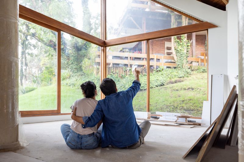 A couple sitting on the floor and planning the remodel of the house they shared equity together.