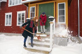 two women shoveling snow from steps of house