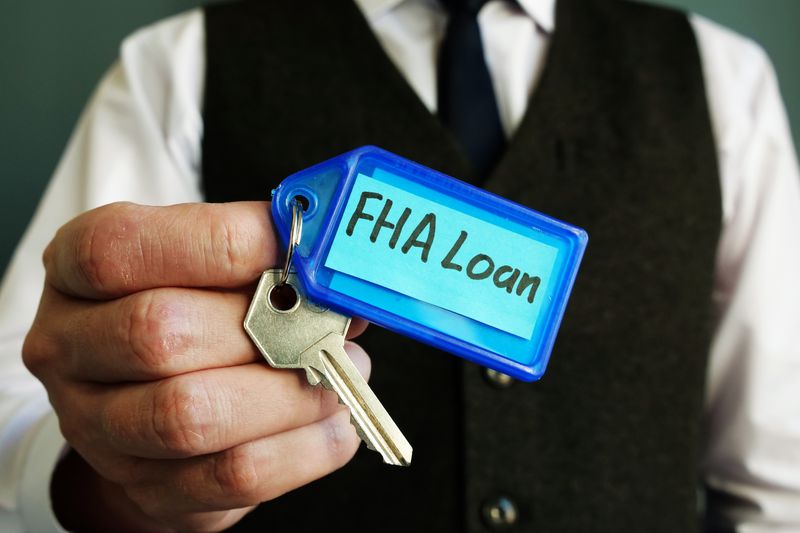 The key with FHA loan sign is in a person's hands.