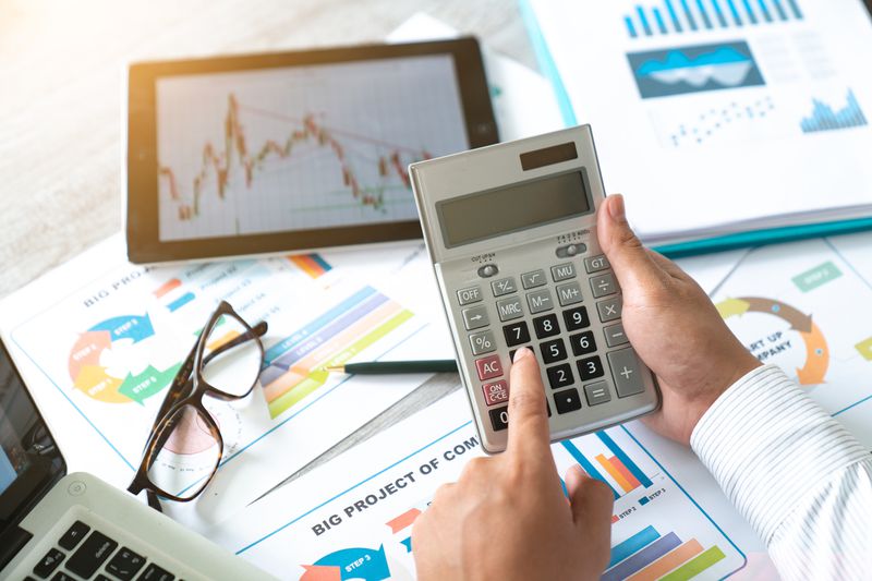 A businessman accountant using a calculator and a laptop for calculating finance on a desk office.