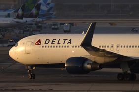A side profile of a Delta Air Lines plane is seen on an airport tarmac.
