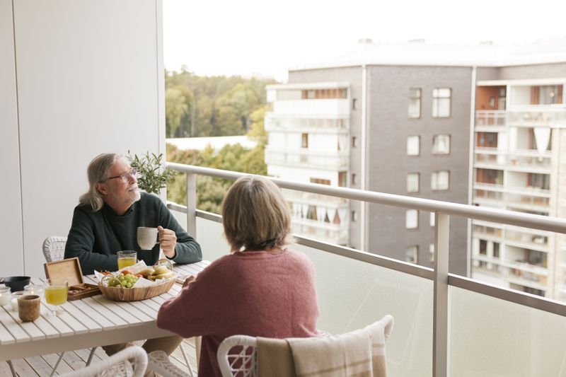 An older couple sitting on the balcony of their landominium. 
