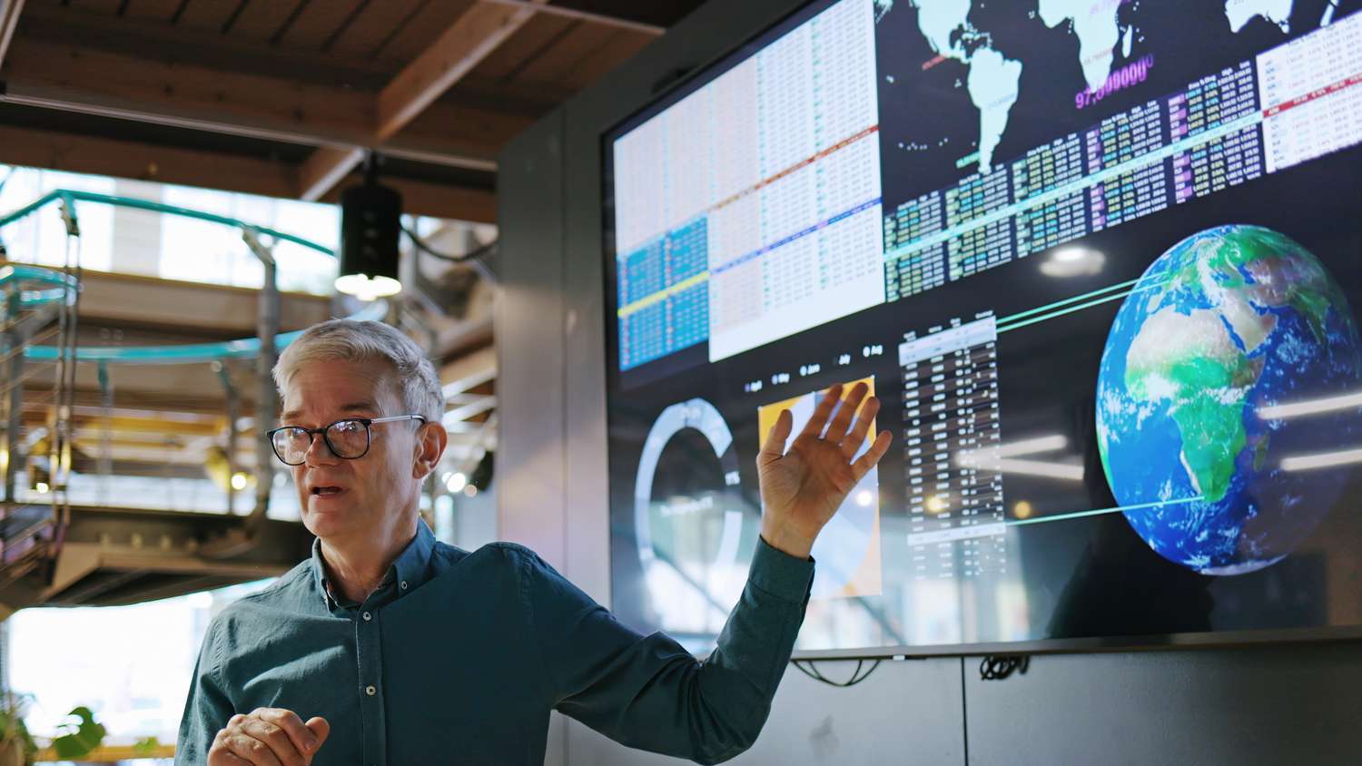 Man standing before a screen showing a globe