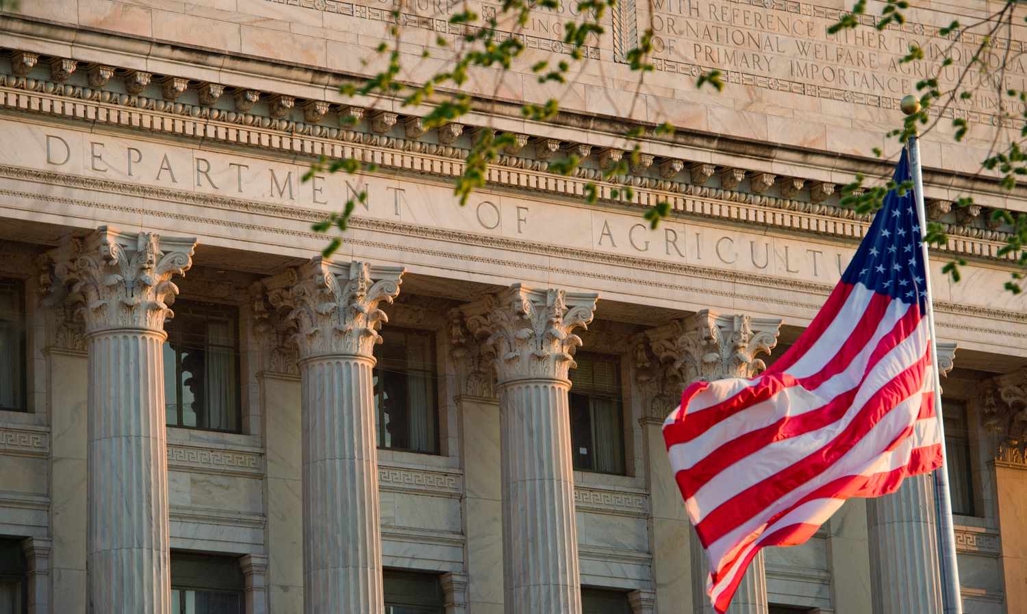 An American flag flaps in the wind in front of the U.S. Department of Agriculture building.