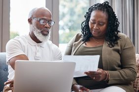 Older couple sitting at home and looking at mortgage documents and a laptop together