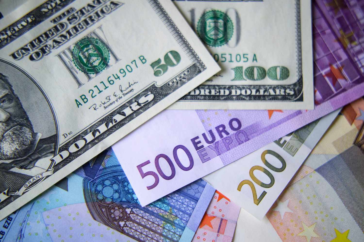 A $50 and $100 bill are pictured on top of 500 Euro and 200 Euro notes