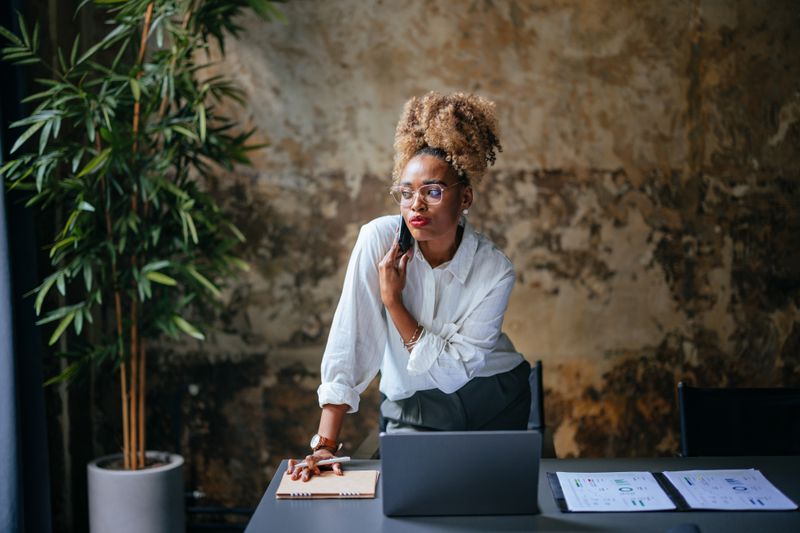 An entrepreneur talks on the phone with their investment banker about setting the price-per-share for their upcoming initial public offering.