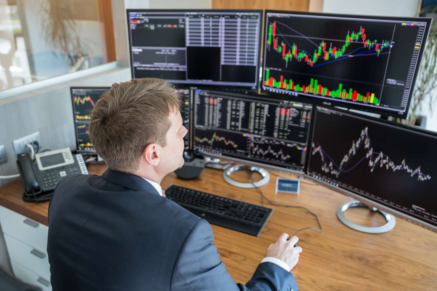 A trader at a brokerage house uses a computer and multiple monitors to split an order to fill it using the liquidity at the best price available.