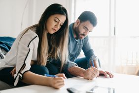Young couple sitting on their sofa and working together on mortgage calculations