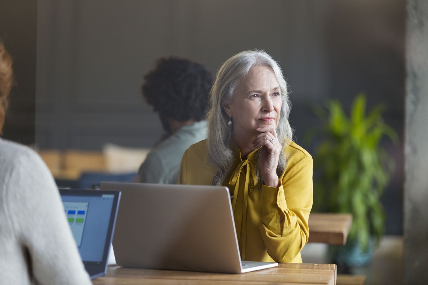 office woman with a laptop in front gazing outside pensively