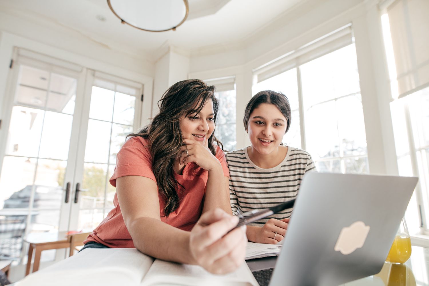 Mom and teenage daughter looking at laptop together, smiling