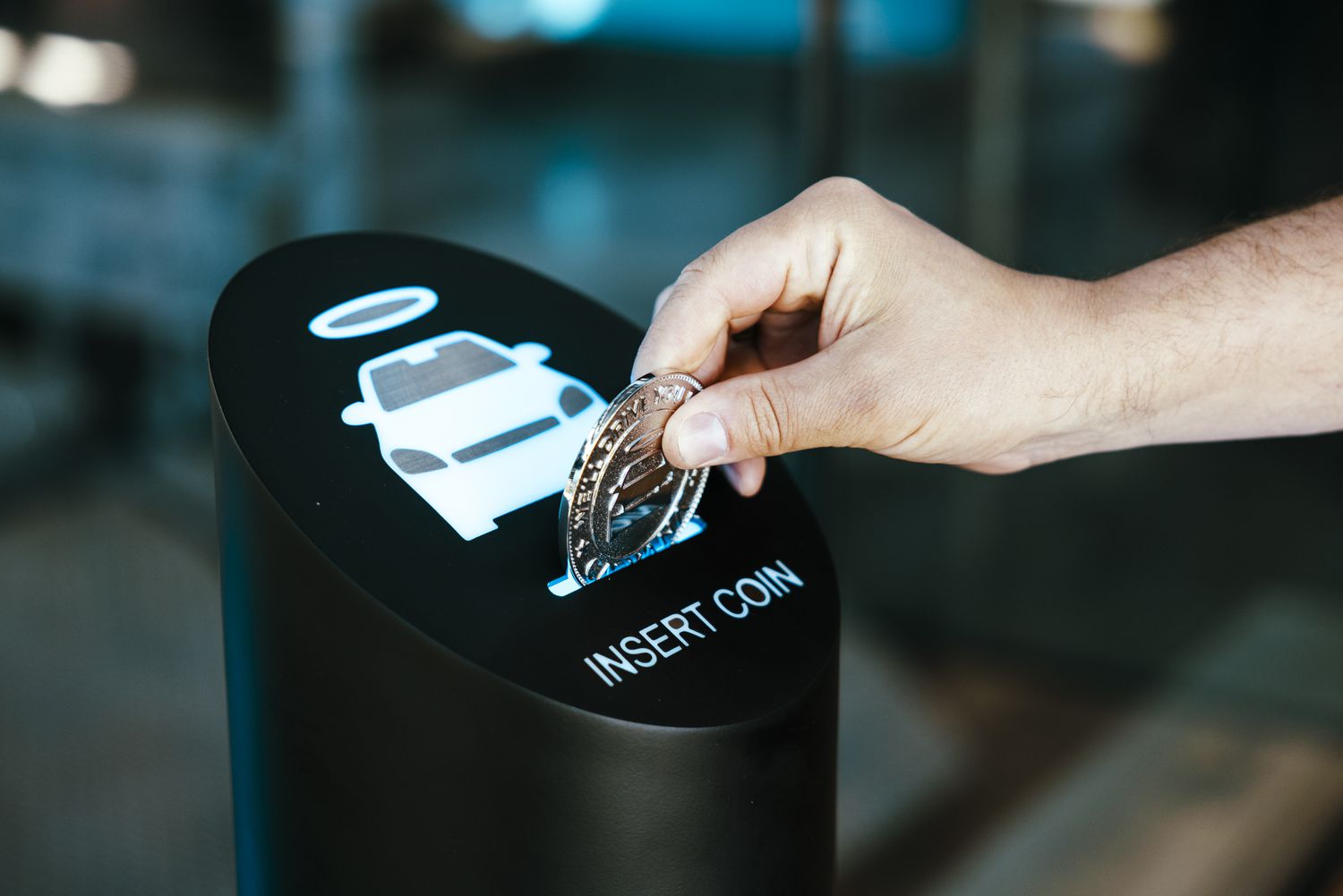 A worker demonstrates a token used to dispense cars at a Carvana vending machine location.