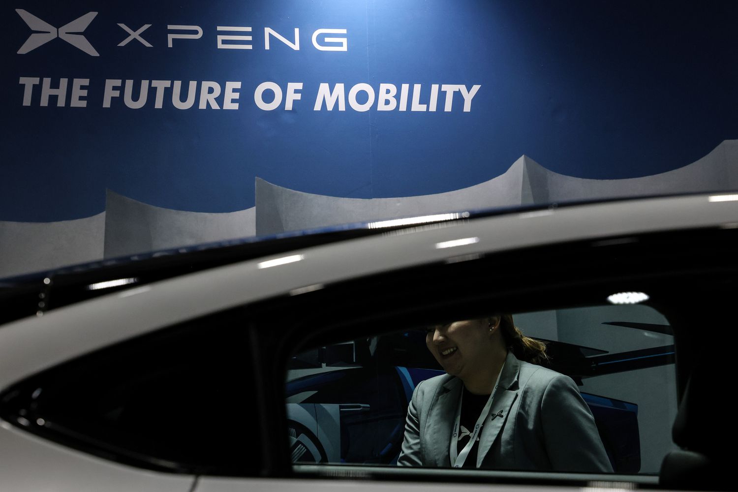 An exhibitor stands behind a Chinese-manufactured Xpeng G6 electric car during ASEAN Sustainable Energy Week and Electric Vehicle Asia 2024 at Queen Sirikit National Convention Center in Bangkok, Thailand on July 5, 2024