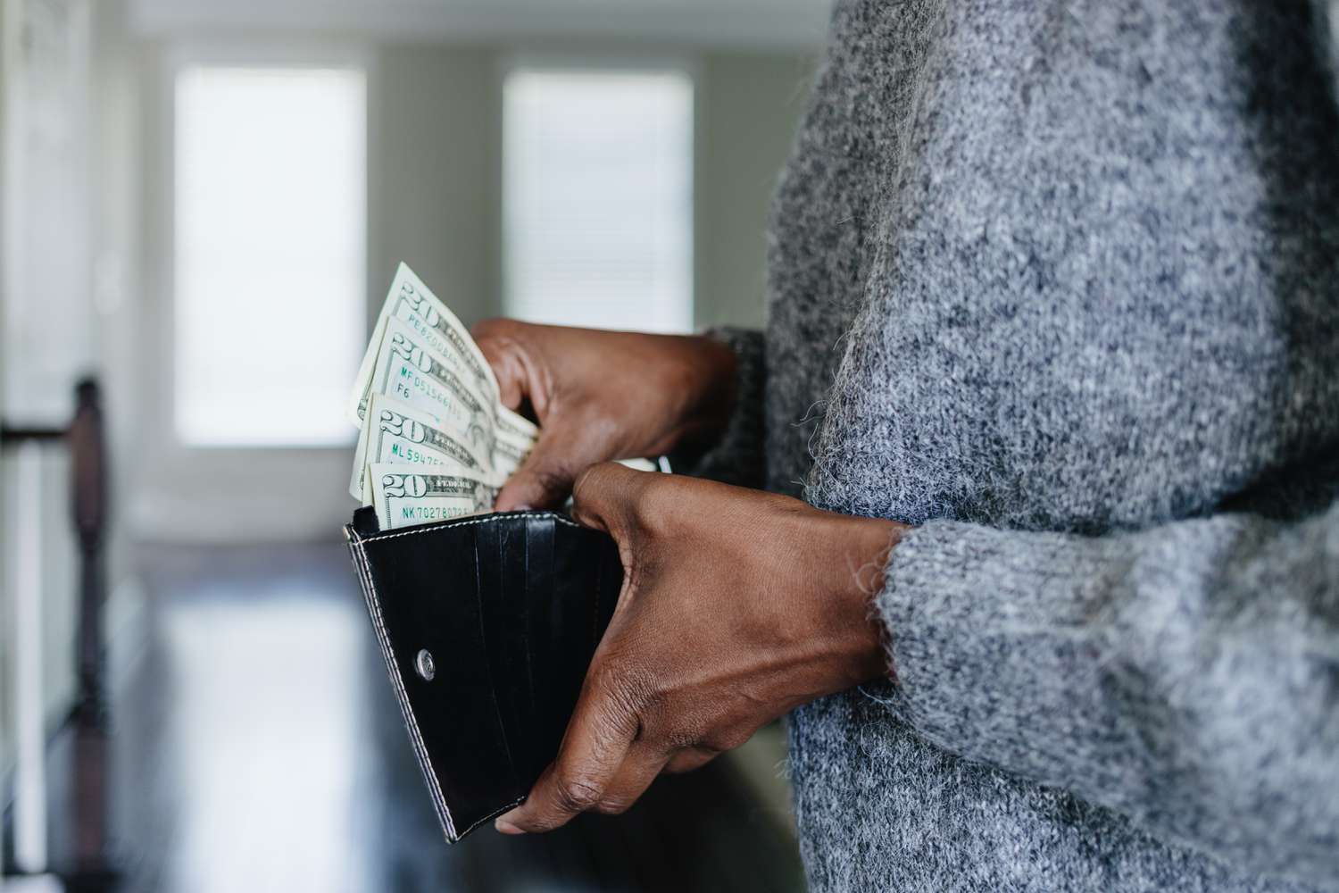 Close-up of woman inserting twenty dollar bills into her wallet