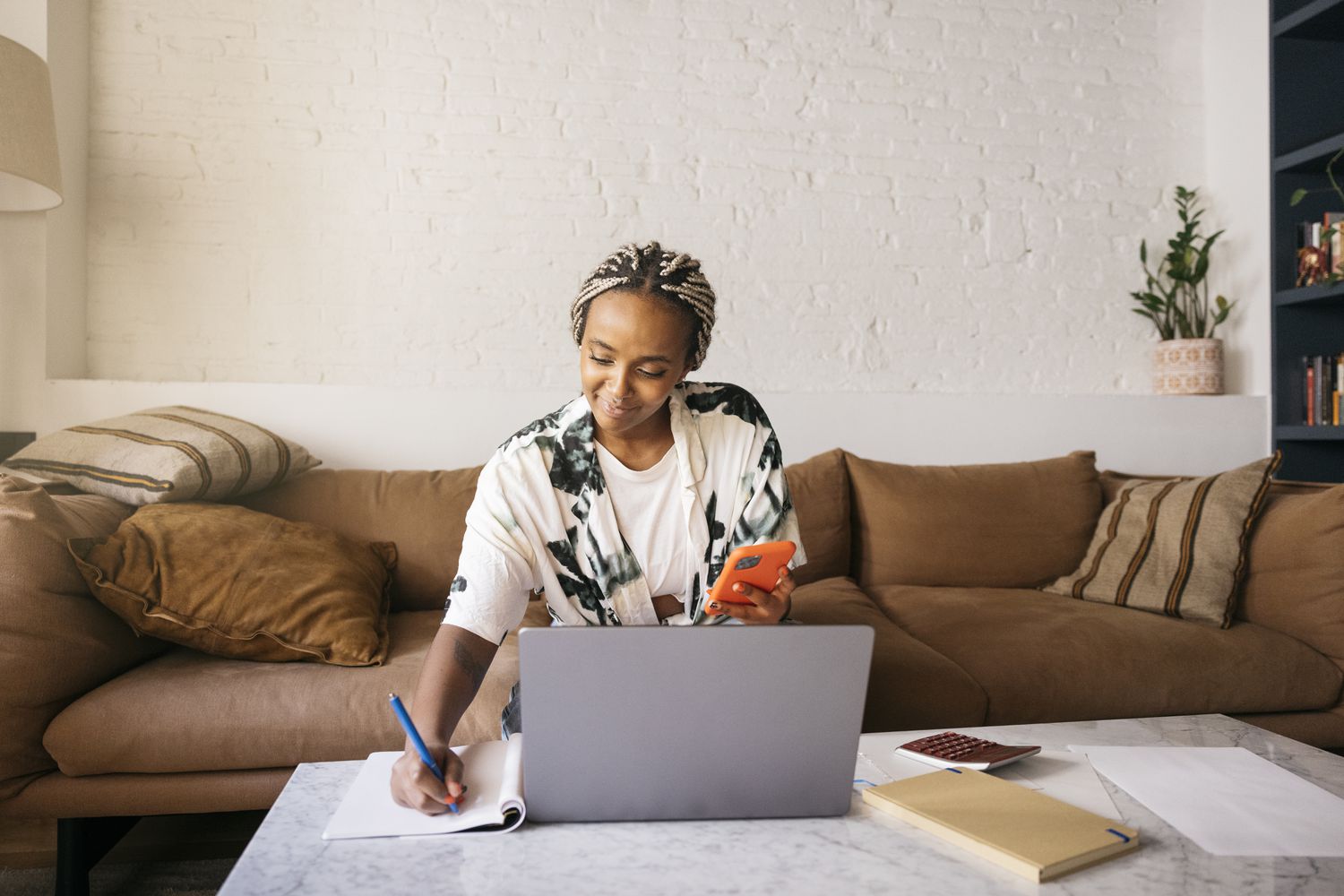 A person sitting on a sofa and using a laptop at a coffee table to calculate investment returns.