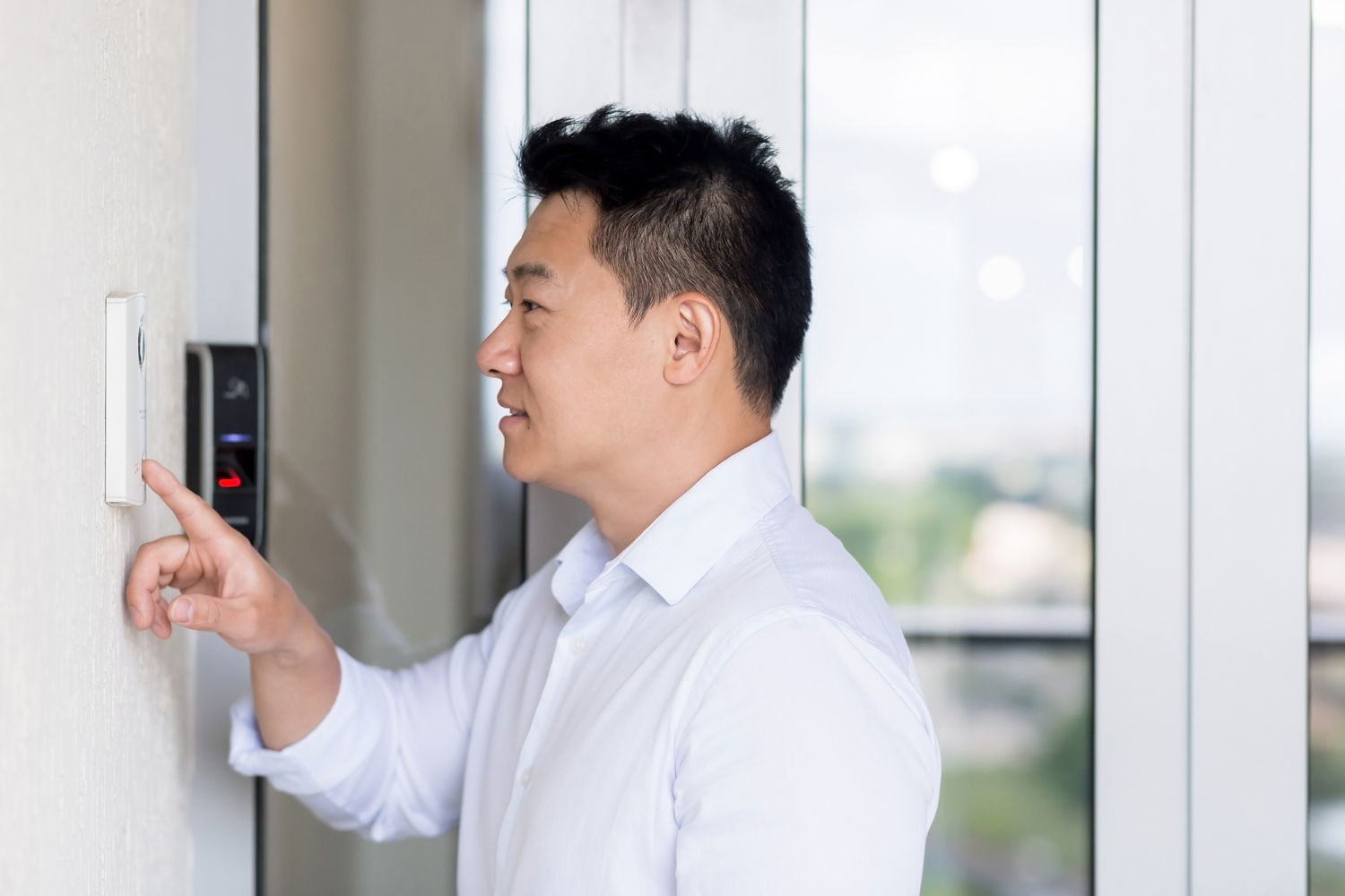 Asian man ringing a Ring video doorbell