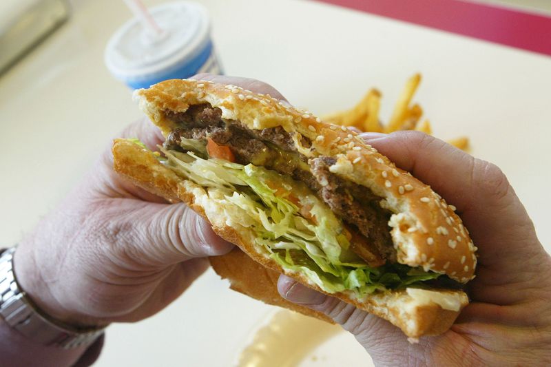A person holding a hamburger with bites already taken out of it.