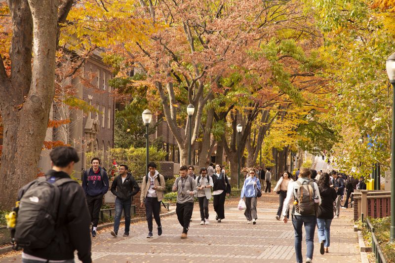 College students walk beneath Autumn trees on the University of Pennsylvania campus.